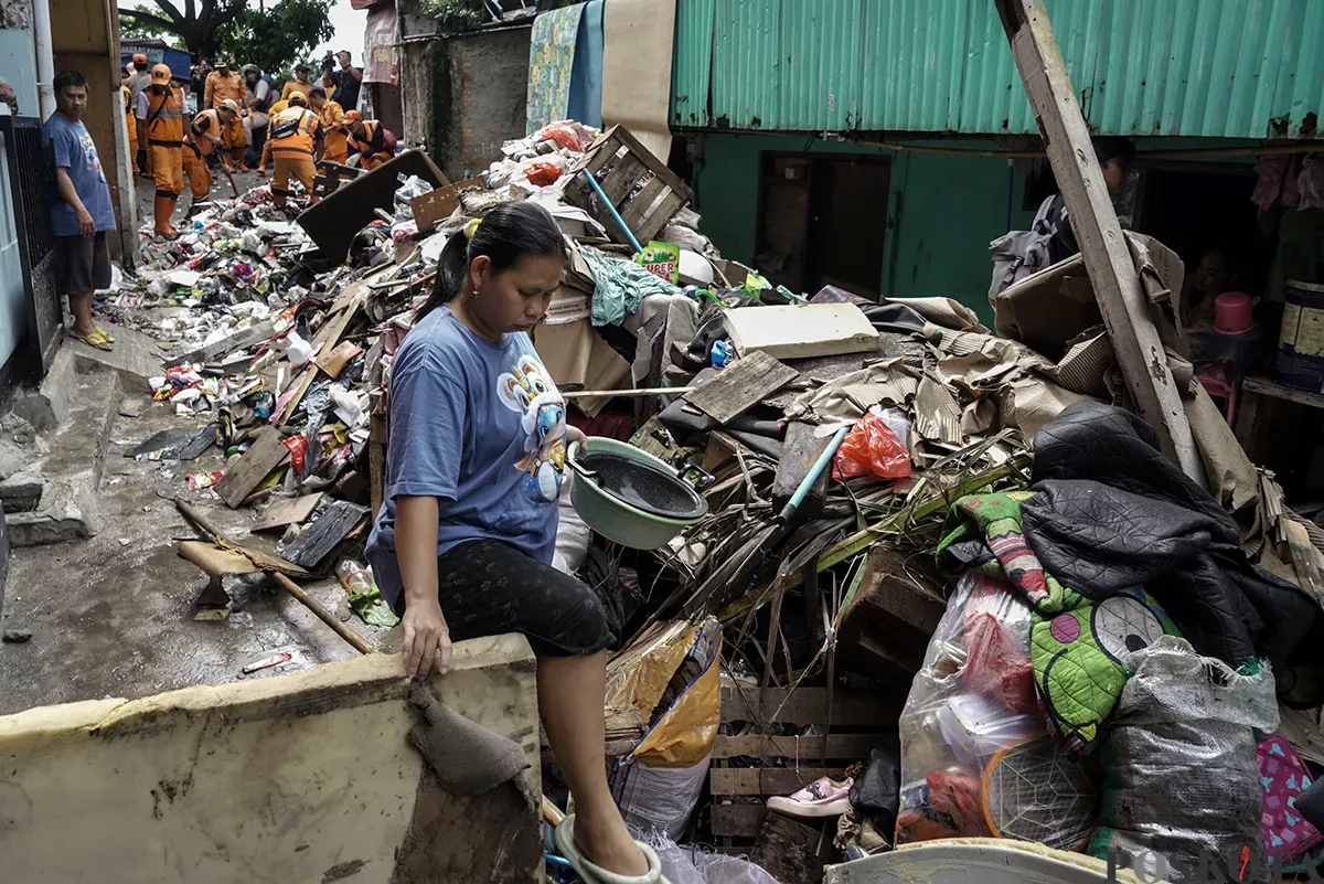 Petugas Penanganan Prasarana dan Sarana Umum (PPSU) Kelurahan Kapuk, mengangkut tumpukan sisa sampah yang terbawa arus air banjir di area gang permukiman pada penduduk di kawasan Jalan Kapuk Bongkaran, Cengkareng, Jakarta Barat, Kamis, 30 Januari 2025. (Sumber: Poskota/ Bilal Nugraha Ginanjar)