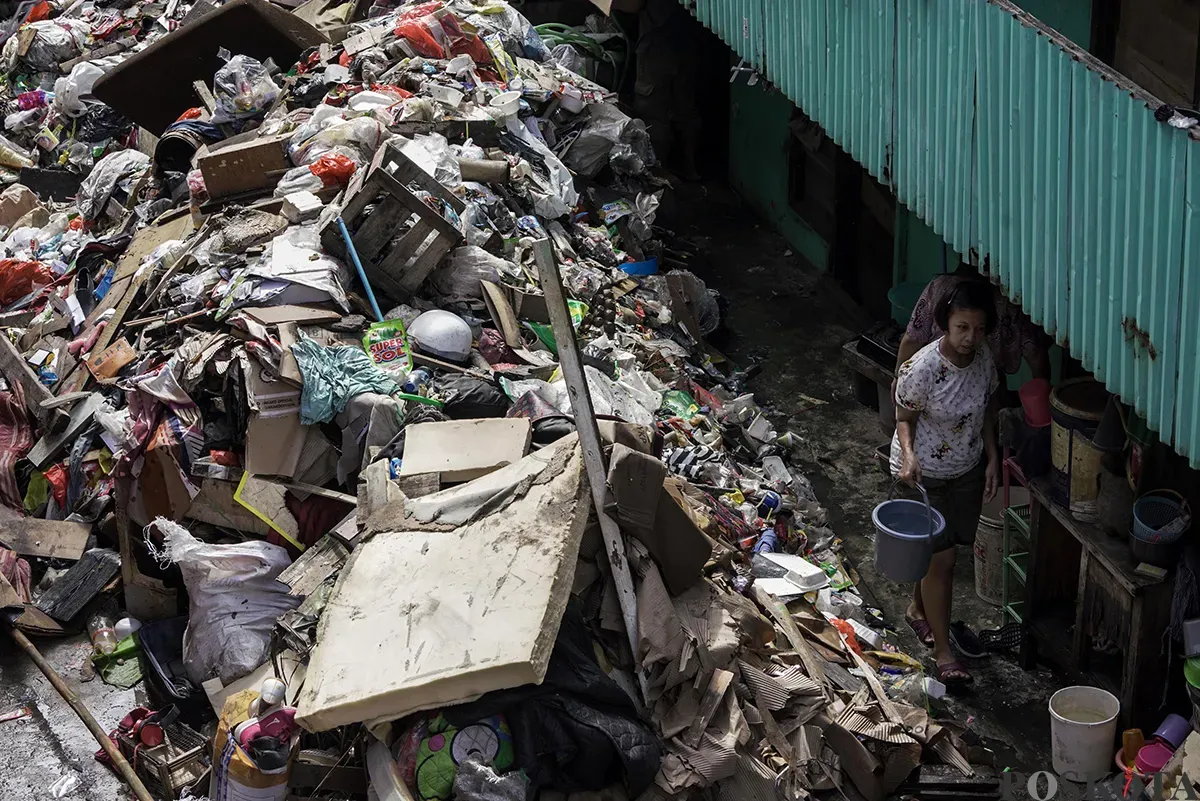 Petugas Penanganan Prasarana dan Sarana Umum (PPSU) Kelurahan Kapuk, mengangkut tumpukan sisa sampah yang terbawa arus air banjir di area gang permukiman pada penduduk di kawasan Jalan Kapuk Bongkaran, Cengkareng, Jakarta Barat, Kamis, 30 Januari 2025. (Sumber: Poskota/ Bilal Nugraha Ginanjar)