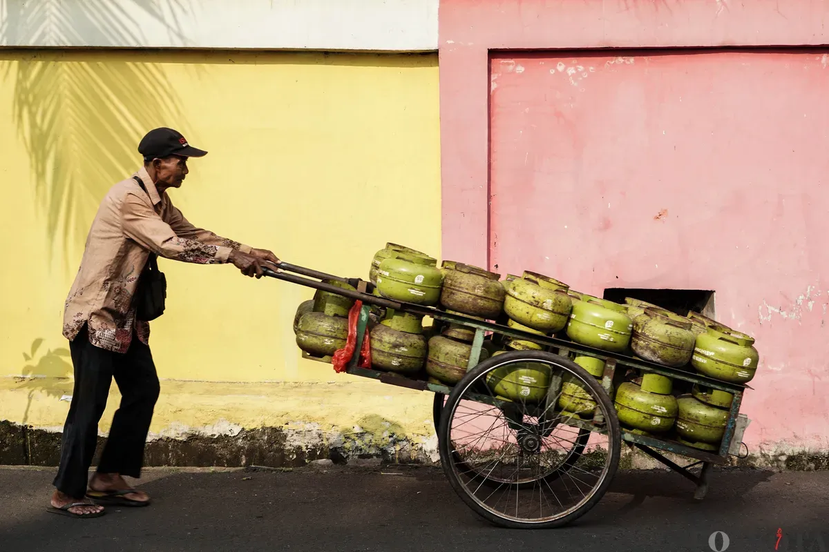 Penjual elpiji subsidi 3 kg mendorong gerobak yang akan diantarkan ke rumah warga di Kawasan Palmerah, Jakarta, Jum'at, 4 Juli 2025. (Sumber: Poskota/Bilal Nugraha Ginanjar)