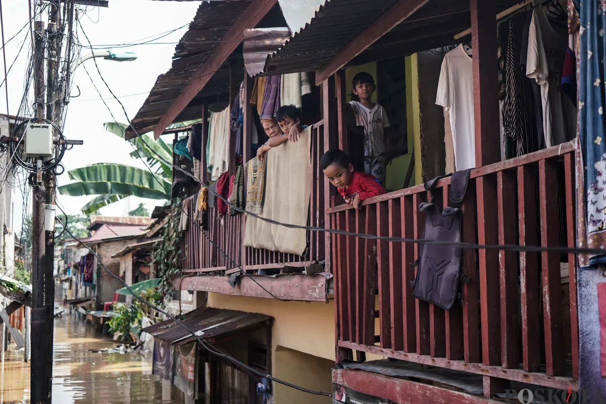 Warga beraktifitas di atas rumah yang dilanda banjir di Jalan Pirus, Bidara Cina, Jatinegara, Jakarta Timur, Minggu, 8 Juli 2025. (Sumber: Poskota/Bilal Nugraha Ginanjar)