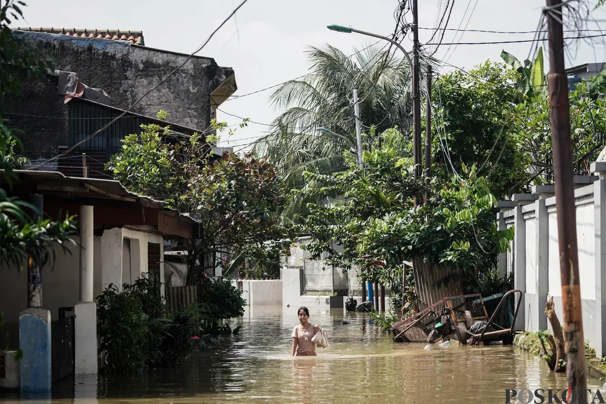 Warga berjalan melintasi banjir di Jalan Pirus, Bidara Cina, Jatinegara, Jakarta Timur, Minggu, 8 Juli 2025. (Sumber: Poskota/Bilal Nugraha Ginanjar)