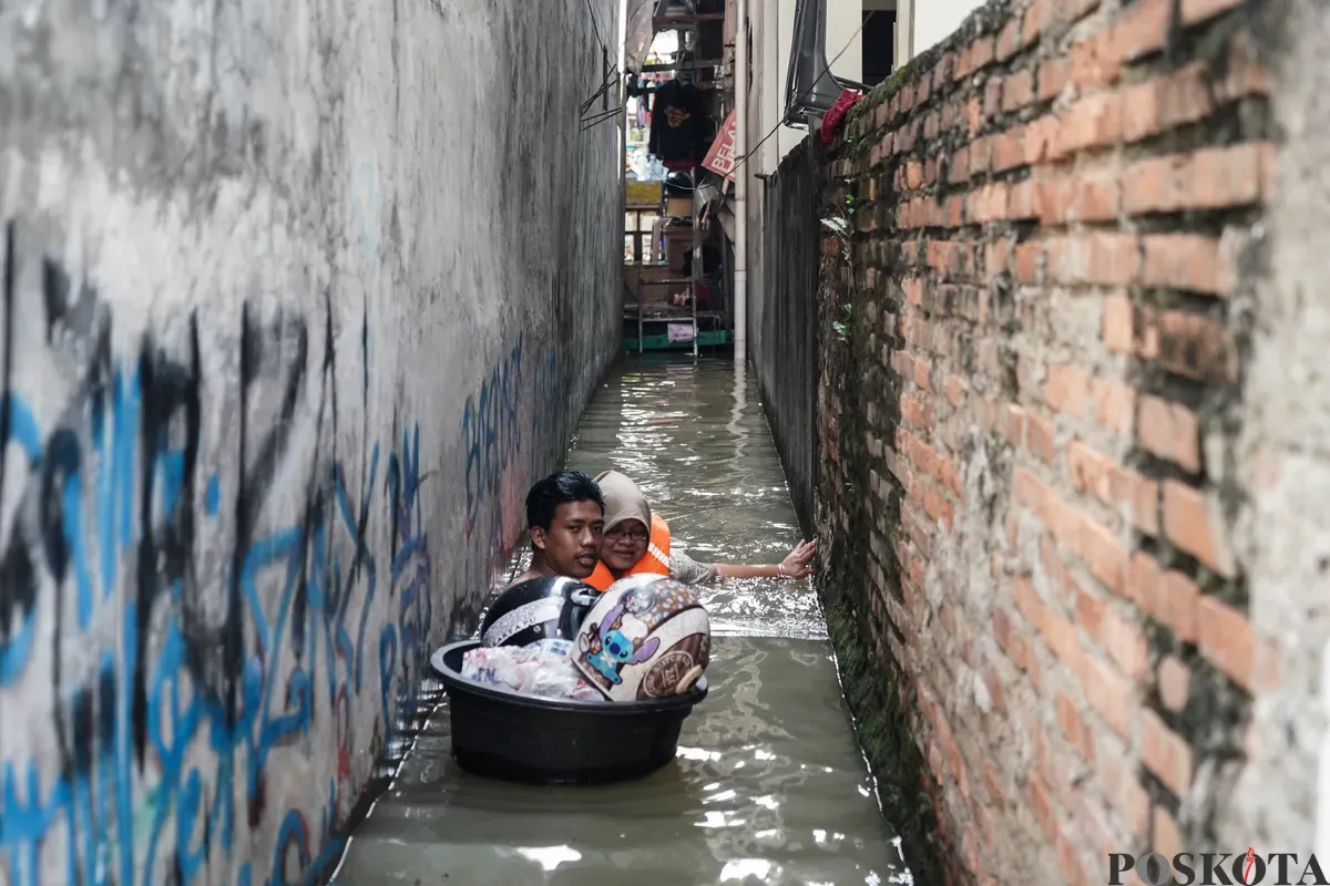 Warga berjalan melintasi banjir di Jalan Pirus, Bidara Cina, Jatinegara, Jakarta Timur, Minggu, 8 Juli 2025. (Sumber: Poskota/Bilal Nugraha Ginanjar)