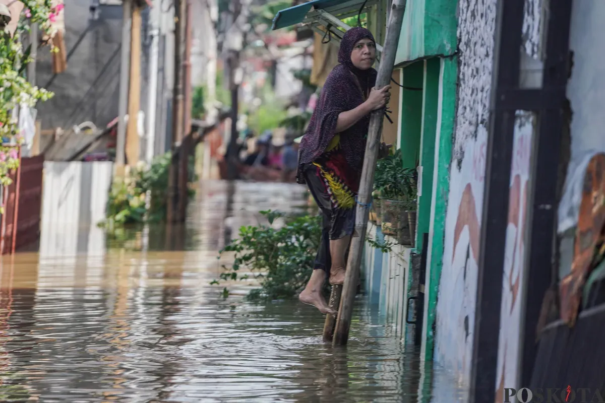 Warga menaiki tangga menuju rumah yang tergenang banjir di Jalan Pirus, Bidara Cina, Jatinegara, Jakarta Timur, Minggu, 8 Juli 2025. (Sumber: Poskota/Bilal Nugraha Ginanjar)
