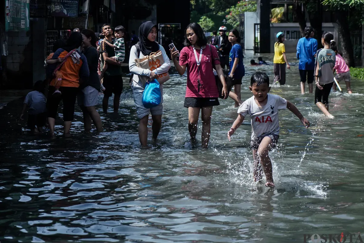 Warga berjalan melintasi banjir di Kampung Makasar, Jakarta Timur, Senin, 7 Juli 2025. (Sumber: Poskota/Bilal Nugraha Ginanjar)