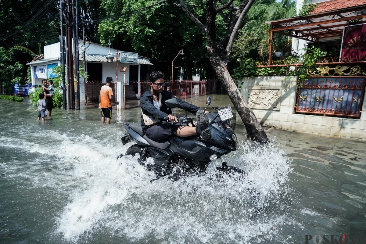 Pengendara sepeda motor melintasi banjir di Kampung Makasar, Jakarta Timur, Senin, 7 Juli 2025. (Sumber: Poskota/Bilal Nugraha Ginanjar)