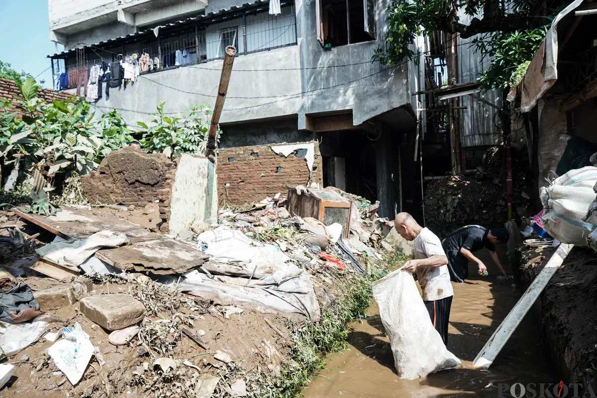 Warga membersihkan sisa sisa lumpur banjir di kawasan pemukiman Rawajati, Pancoran, Jakarta Selatan, Minggu, 7 Juli 2025. (Sumber: Poskota/Bilal Nugraha Ginanjar)
