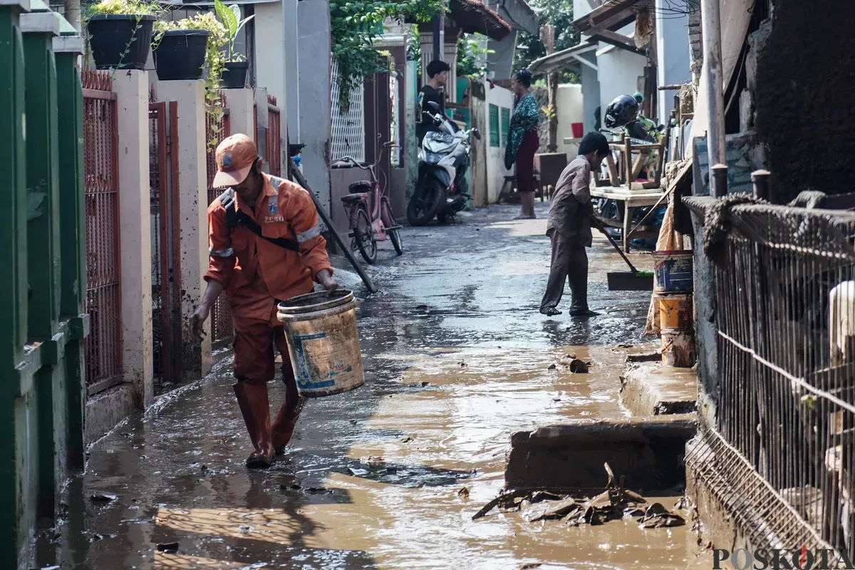 Warga membersihkan sisa sisa lumpur banjir di kawasan pemukiman Rawajati, Pancoran, Jakarta Selatan, Minggu, 7 Juli 2025. (Sumber: Poskota/Bilal Nugraha Ginanjar)