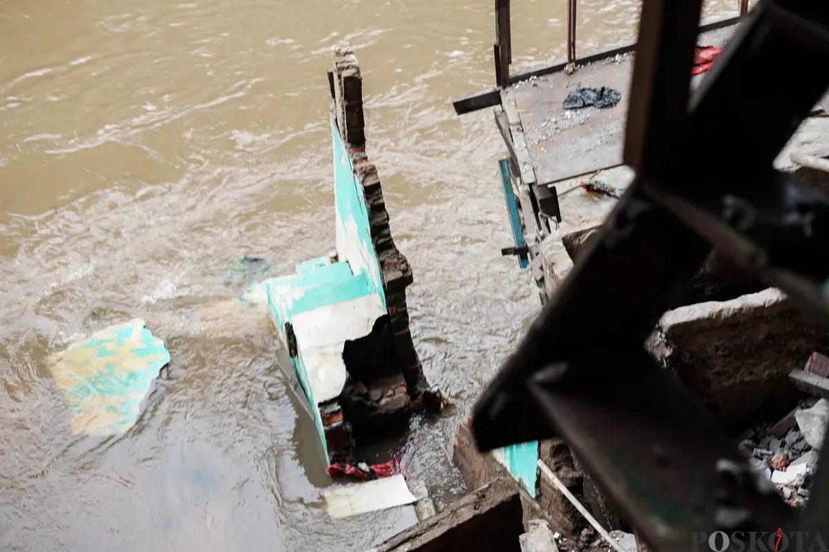 Warga melihat kondisi rumahnya yang mengalami longsor di bantaran Sungai Ciliwung di Jalan Slamet Riyadi I, Kebon Manggis, Matraman, Jakarta Timur, Kamis, 10 Juli 2025. (Sumber: Poskota/Bilal Nugraha Ginanjar)