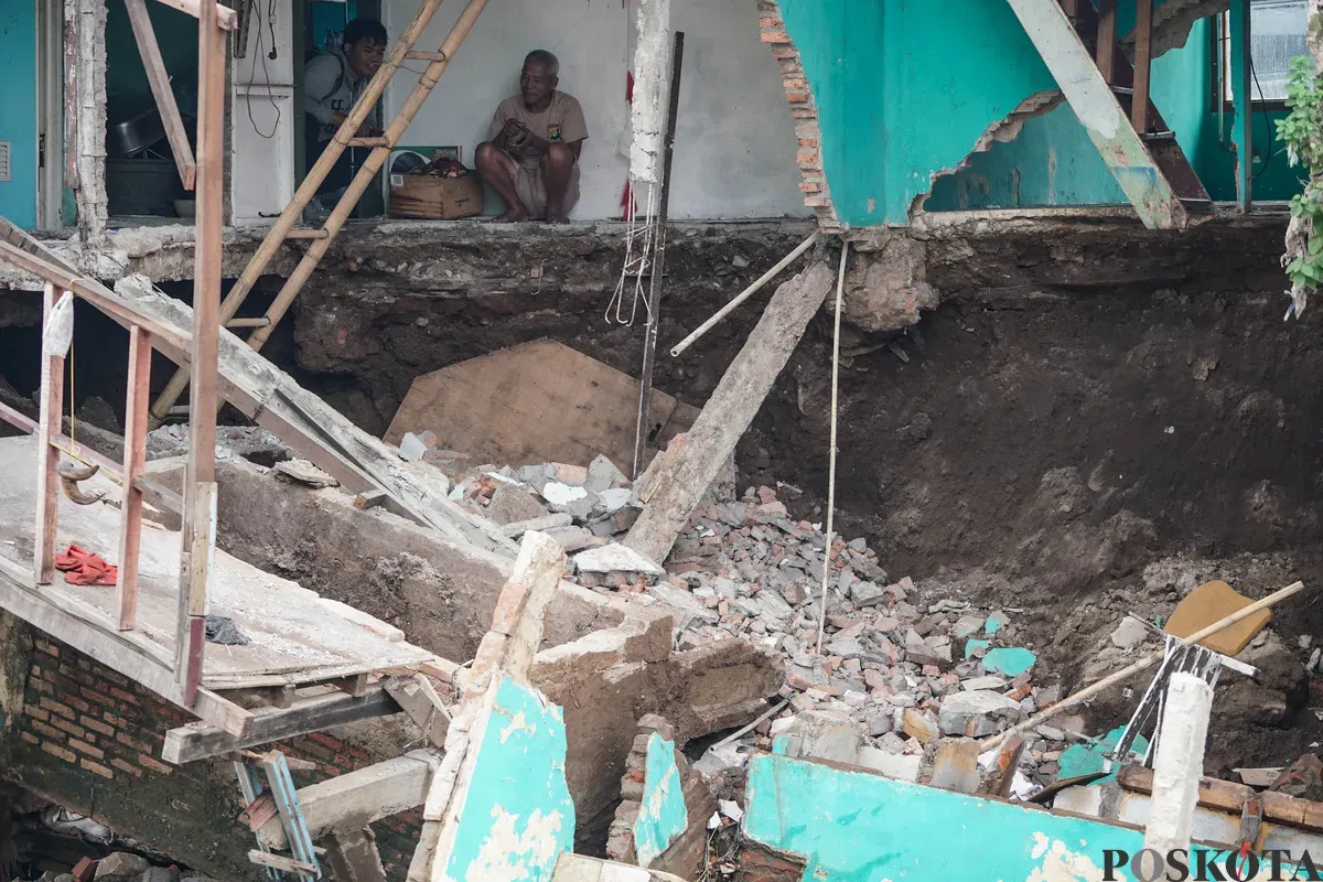 Warga melihat kondisi rumahnya yang mengalami longsor di bantaran Sungai Ciliwung di Jalan Slamet Riyadi I, Kebon Manggis, Matraman, Jakarta Timur, Kamis, 10 Juli 2025. (Sumber: Poskota/Bilal Nugraha Ginanjar)