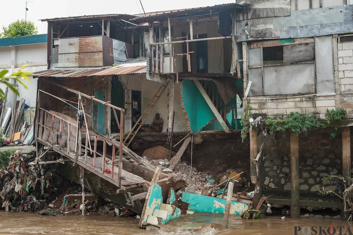 Warga melihat kondisi rumahnya yang mengalami longsor di bantaran Sungai Ciliwung di Jalan Slamet Riyadi I, Kebon Manggis, Matraman, Jakarta Timur, Kamis, 10 Juli 2025. (Sumber: Poskota/Bilal Nugraha Ginanjar)