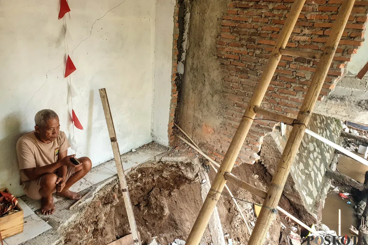 Warga melihat kondisi rumahnya yang mengalami longsor di bantaran Sungai Ciliwung di Jalan Slamet Riyadi I, Kebon Manggis, Matraman, Jakarta Timur, Kamis, 10 Juli 2025. (Sumber: Poskota/Bilal Nugraha Ginanjar)