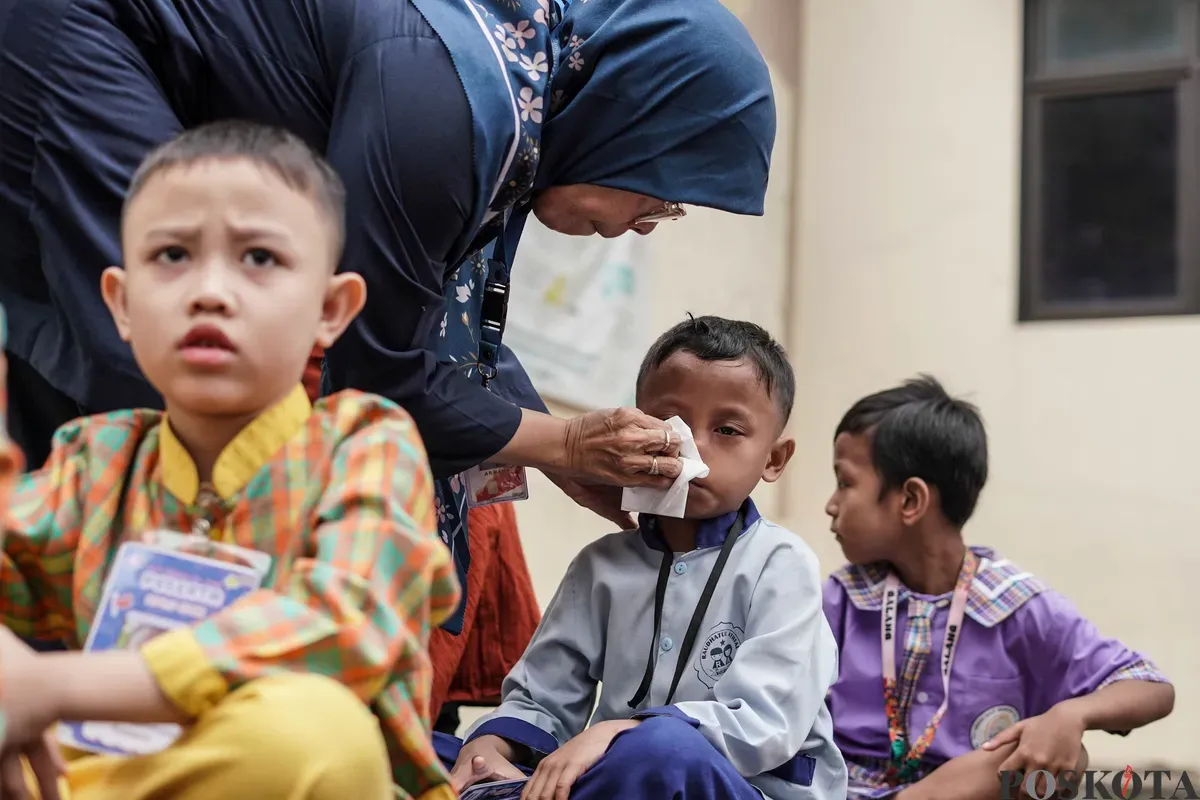 Guru membersihkan air mata siswa baru pada kegiatan MPLS di SDN Karet 01, Jakarta, Senin, 14 Juli 2025. (Sumber: Poskota/Bilal Nugraha Ginanjar)