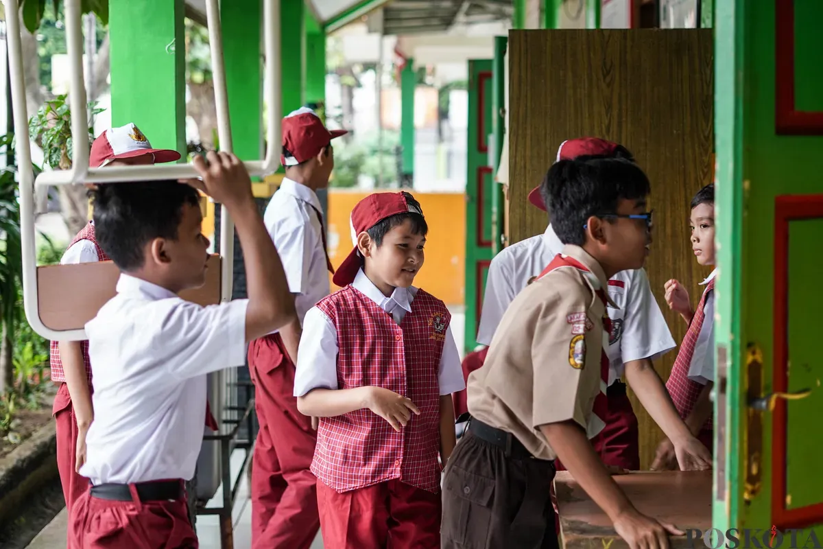 Sejumlah siswa membawa bangku ke dalam kelas di SDN Karet 01, Jakarta, Senin, 14 Juli 2025. (Sumber: Poskota/Bilal Nugraha Ginanjar)