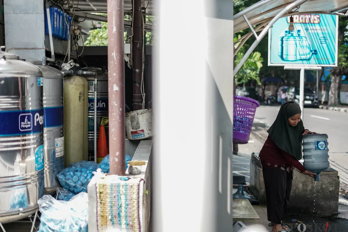 Warga mengisi botol air galon di depot air minum gratis di Jalan Rawamangun Muka Selatan, Jakarta Timur, Selasa, 15 Juli 2025. (Sumber: Poskota/Bilal Nugraha Ginanjar)