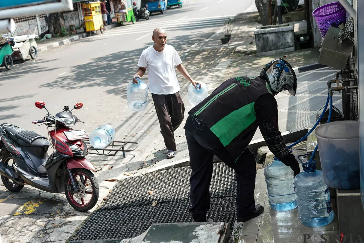 Warga mengisi botol air galon di depot air minum gratis di Jalan Rawamangun Muka Selatan, Jakarta Timur, Selasa, 15 Juli 2025. (Sumber: Poskota/Bilal Nugraha Ginanjar)