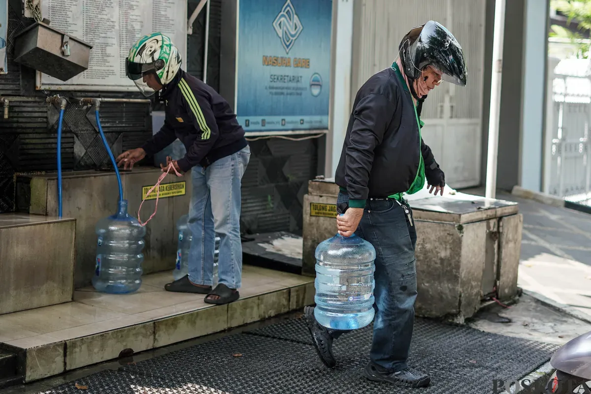 Warga mengisi botol air galon di depot air minum gratis di Jalan Rawamangun Muka Selatan, Jakarta Timur, Selasa, 15 Juli 2025. (Sumber: Poskota/Bilal Nugraha Ginanjar)