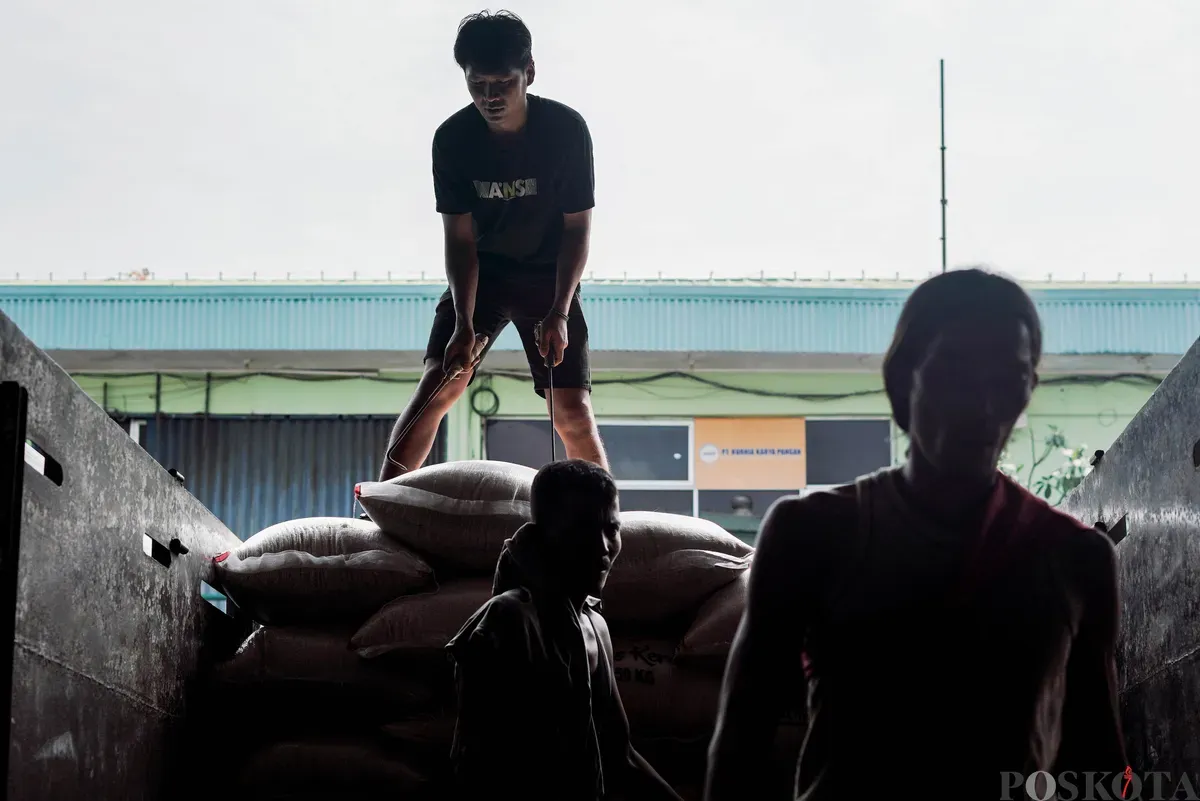 Pekerja mengangkat karung beras di Pasar Beras Cipinang, Jakarta Timur, Selasa, 15 Juli 2025. (Sumber: Poskota/Bilal Nugraha Ginanjar)