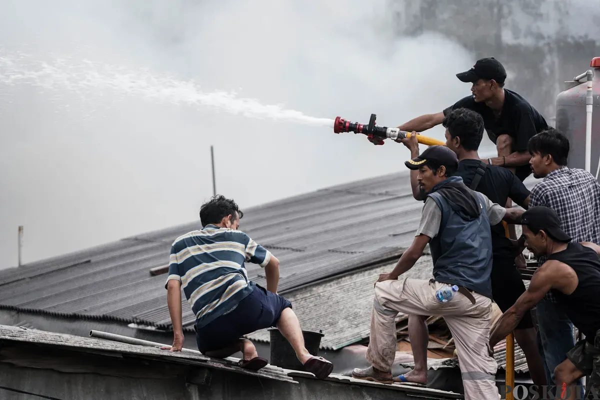 Warga bergotong roryong memadamkan api yang membakar pemukiman padat penduduk di kawasan Grogol Utara, Kebayoran Lama, Jakarta Selatan, Minggu, 20 Juli 2025. (Sumber: Poskota/Bilal Nugraha Ginanjar)
