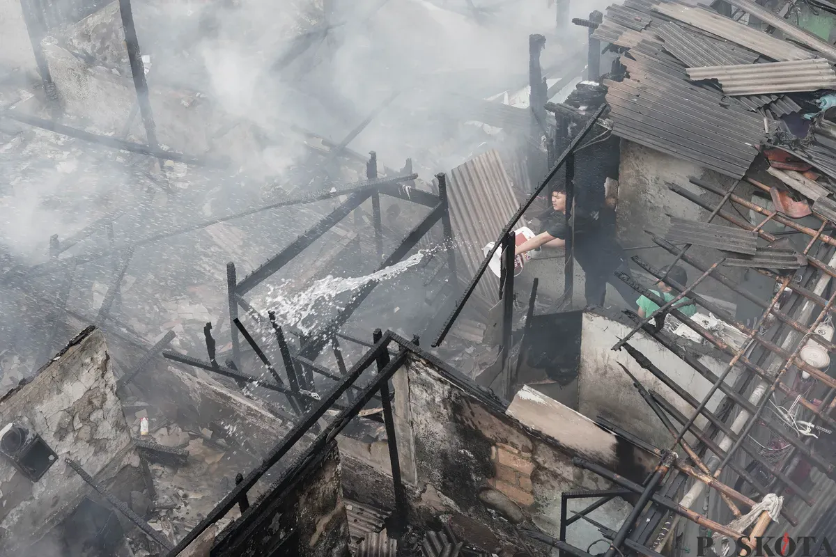 Warga memadamkan api yang membakar pemukiman padat penduduk di kawasan Grogol Utara, Kebayoran Lama, Jakarta Selatan, Minggu, 20 Juli 2025. (Sumber: Poskota/Bilal Nugraha Ginanjar)