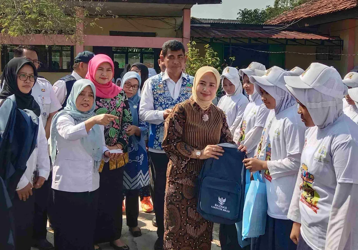 Wakil Bunda Forum Anak Daerah Kabupaten Bekasi, Nia Asep Surya Atmaja memberikan bantuan peralatan sekolah dari Baznas dan Bank Bjb, kepada puluhan siswa, di acara Botram Sekolah dan peringatan HAN di SMAN 1 Tambelang (Sumber: Dok. Pemkab Bekasi)