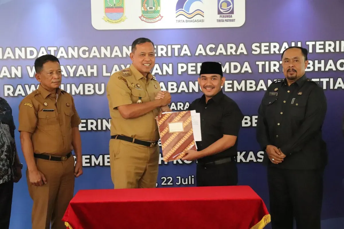 Bupati Bekasi Ade Kuswara Kunang dan Walikota Bekasi Tri Adhianto menandatangani berita acara serah terima aset dan layanan Perumda Tirta Bhagasasi Cabang Rawalumbu dan Cabang Pembantu Setia Mekar, di Pemkot Bekasi. (Sumber: Dok. Pemkab Bekasi)