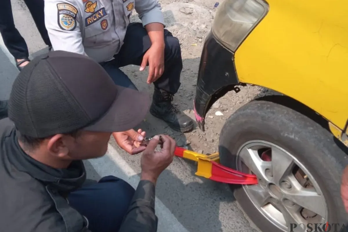 Petugas mengunci ban mobil dalam penertiban di kawasan Padalarang, Kabupaten Bandung Barat, Rabu, 23 Juli 2025. (Sumber: Poskota/Gatot Poedji Utomo)