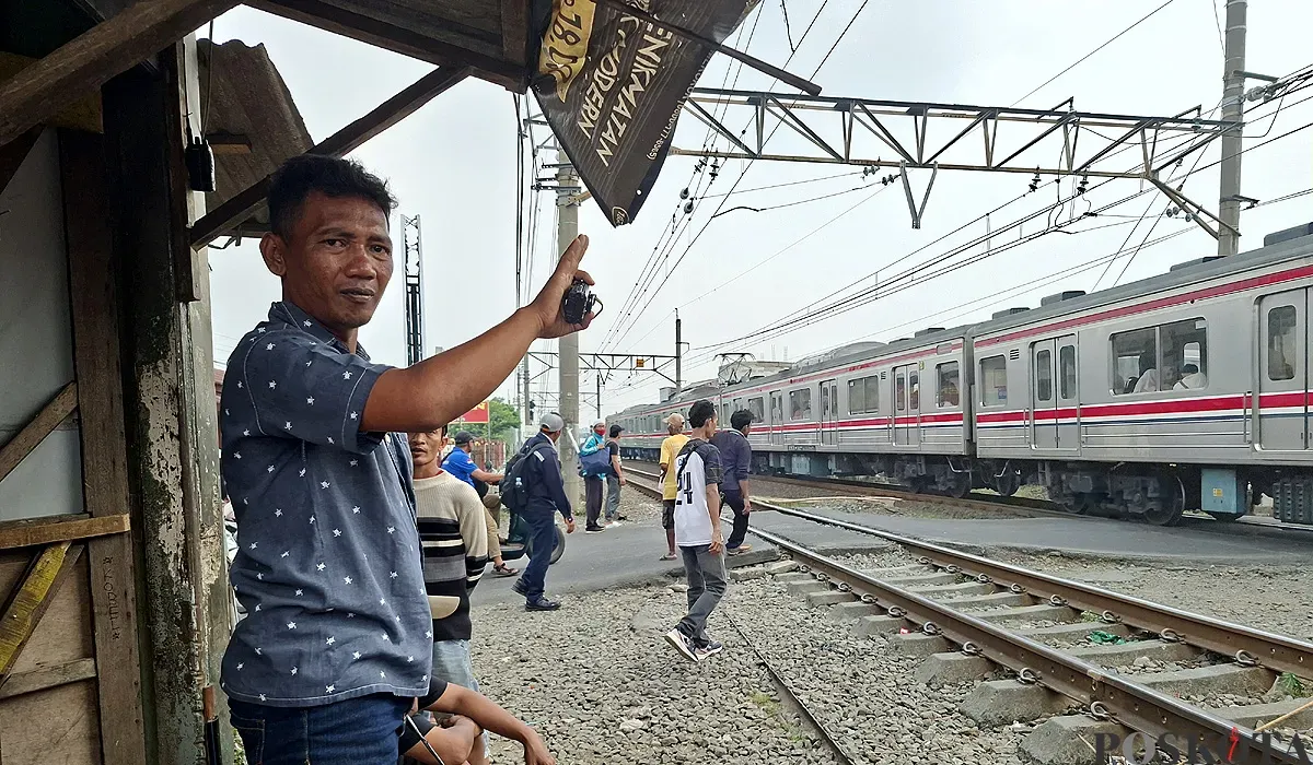 Khadafi saat menjaga perlintasan rel kereta liar di Perumahan Gaperi, Bojonggede, Sabtu sore, 26 Juli 2025. (Sumber: POSKOTA | Foto: Angga Pahlevi)