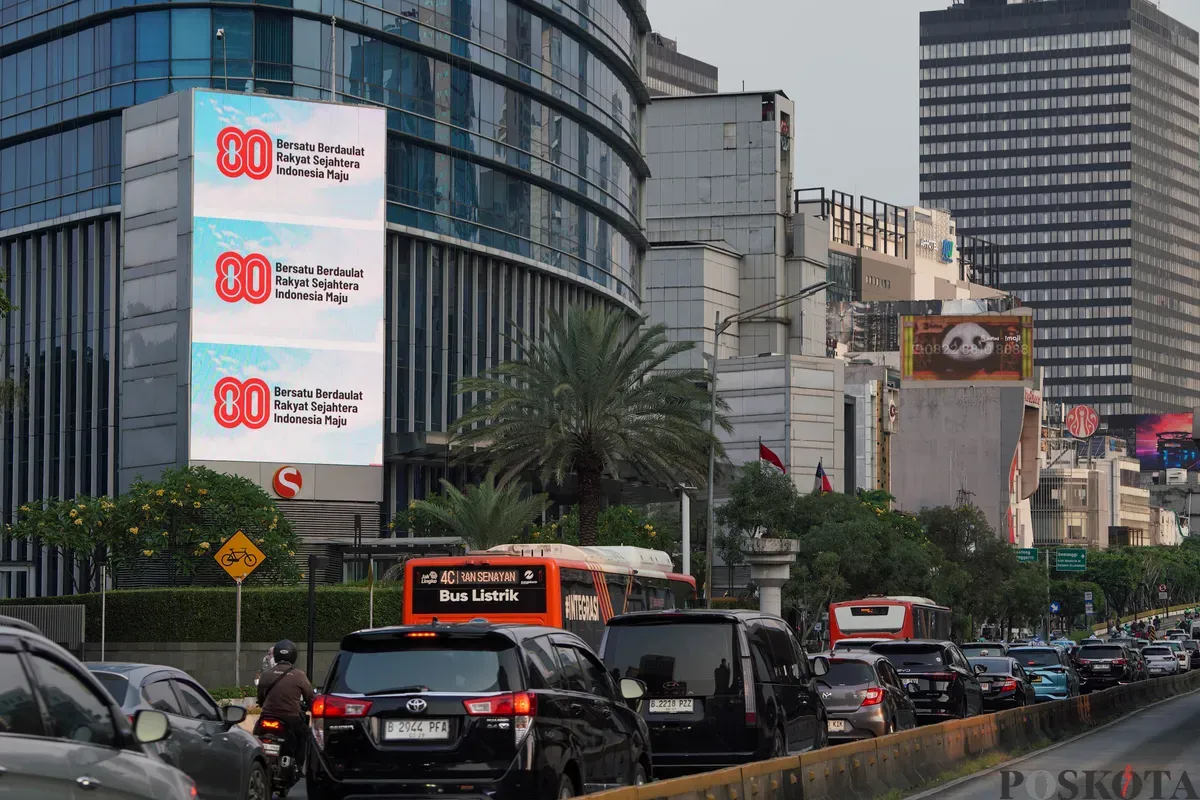 Sejumlah kendaraan melintas di dekat Videotron yang menampilkan logo HUT RI ke-80 di kawasan Jalan Sudirman, Jakarta, Kamis, 24 Juli 2025. (Sumber: Poskota/Bilal Nugraha Ginanjar)