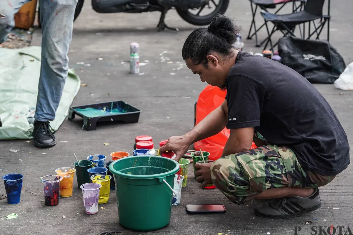 Pelukis mural atau muralis menyelesaikan karyanya di kawasan Kalipasir, Cikini, Jakarta, Kamis, 24 Juli 2025. (Sumber: Poskota/Bilal Nugraha Ginanjar)