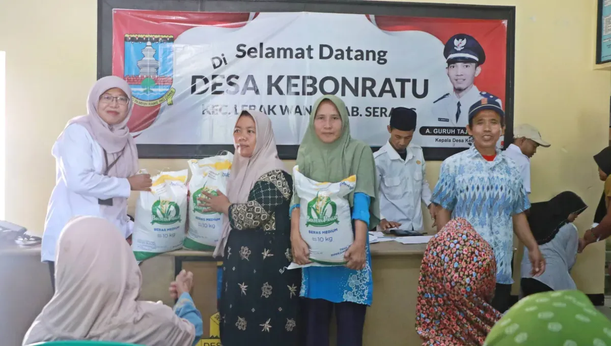 Kabid Ketahanan Pangan DKPP Kabupaten Serang, Mumun Munawaroh (kiri), simbolis menyerahkan bantuan pangan beras kepada KPM di kantor Desa Kebon Ratu, Rabu, 30 Juli 2025. (Sumber: Dok Kominfo Pemkab Serang)