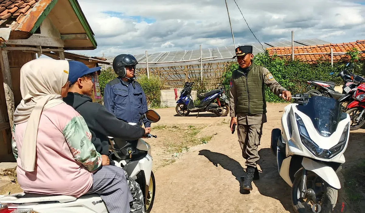 Petugas mengarahkan pengendara motor yang hendak melintas di kawasan tanah bergerak di Desa Cimanggu, Kecamatan Ngamprah, Bandung Barat pada Kamis, 31 Juli 2025. (Sumber: POSKOTA | Foto: Gatot Poedji Utomo)