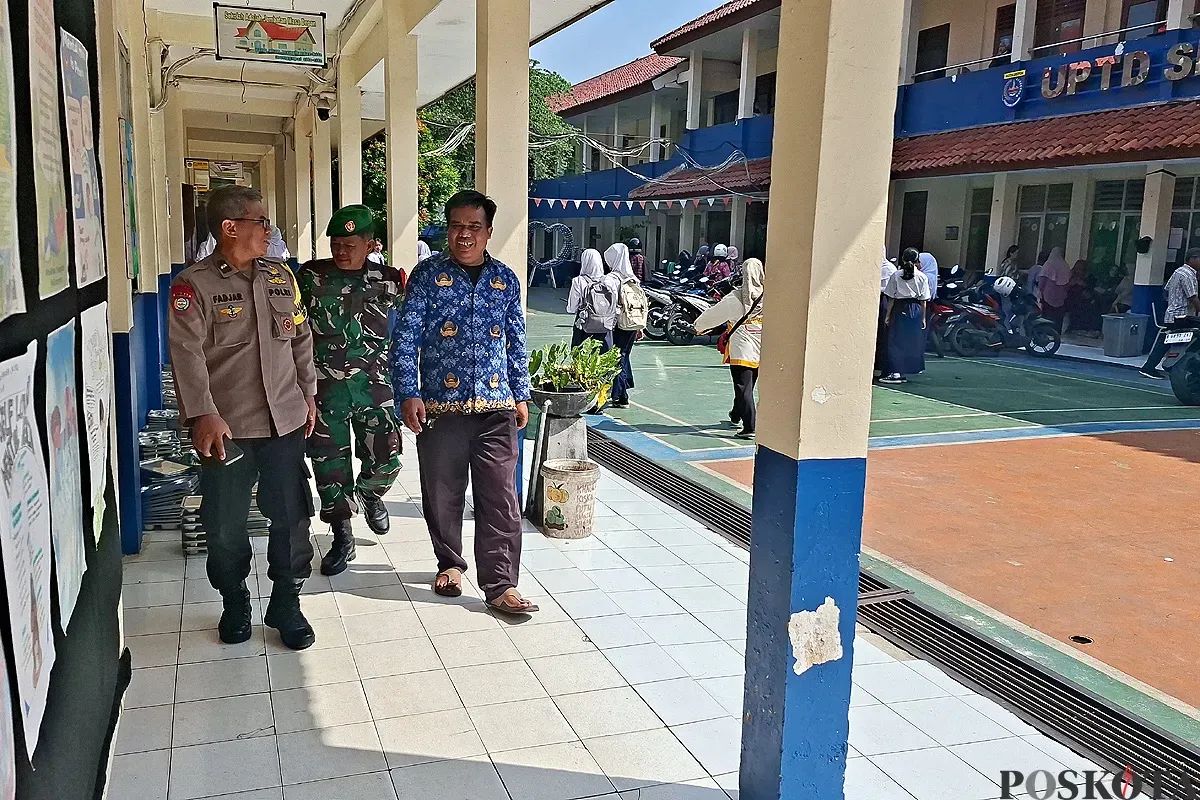 Anggota Bhabinkamtibmas Kelurahan Gandul, Kota Depok, bersama Babinsa melakukan pengamanan pendaftaran SPMB 2025. (Sumber: POSKOTA | Foto: Angga Pahlevi)