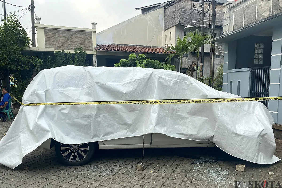Kondisi mobil milik korban M yang tewas terbakar dipasang garis polisi di Perumahan Graha Pondok Kacang, Tangerang Selatan pada Selasa, 3 Juni 2025. (Sumber: POSKOTA | Foto: Primayanti)