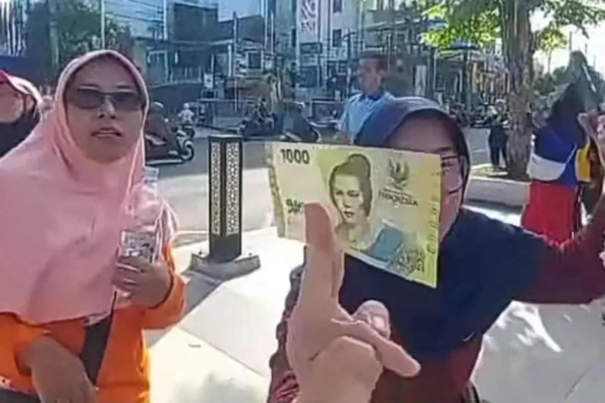 Seorang warga berhasil mendapatkan uang yang disebar dari atas langit Alun-Alun Jember. (Sumber: TikTok/@jawatimurpopuler)