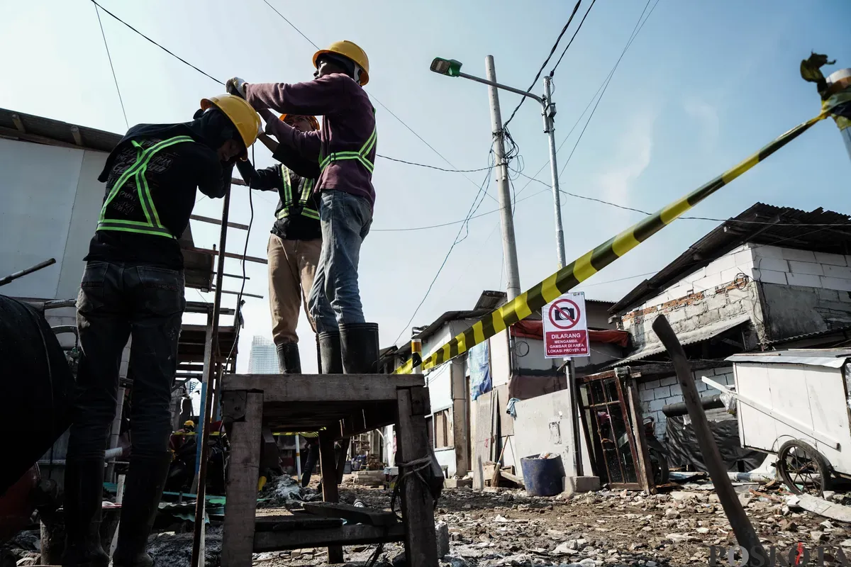 Pekerja menyelesaikan pembangunan tanggul mitigasi banji rob di Jalan Dermaga Ujung, Muara Angke, Jakarta, Kamis, 12 Juni 2025. (Sumber: Poskota/Bilal Nugraha Ginanjar)