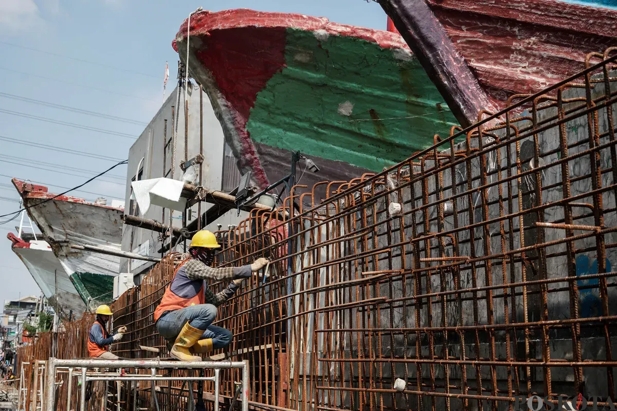 Pekerja menyelesaikan pembangunan tanggul mitigasi di area Docking Kapal Baywalk, Pluit, Jakarta, Kamis, 12 Juni 2025. (Sumber: Poskota/Bilal Nugraha Ginanjar)