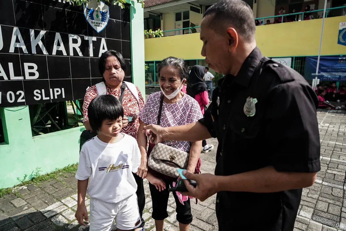 Petugas membagikan nomot antrean kepada Orang tua siswa yang akan mendaftarkan anaknya di Posko Sistem Penerimaan Murid Baru (SPMB) SLB Negeri 5 Jakarta, Senin, 16 Juni 2025. (Sumber: Poskota/Bilal Nugraha Ginanjar)