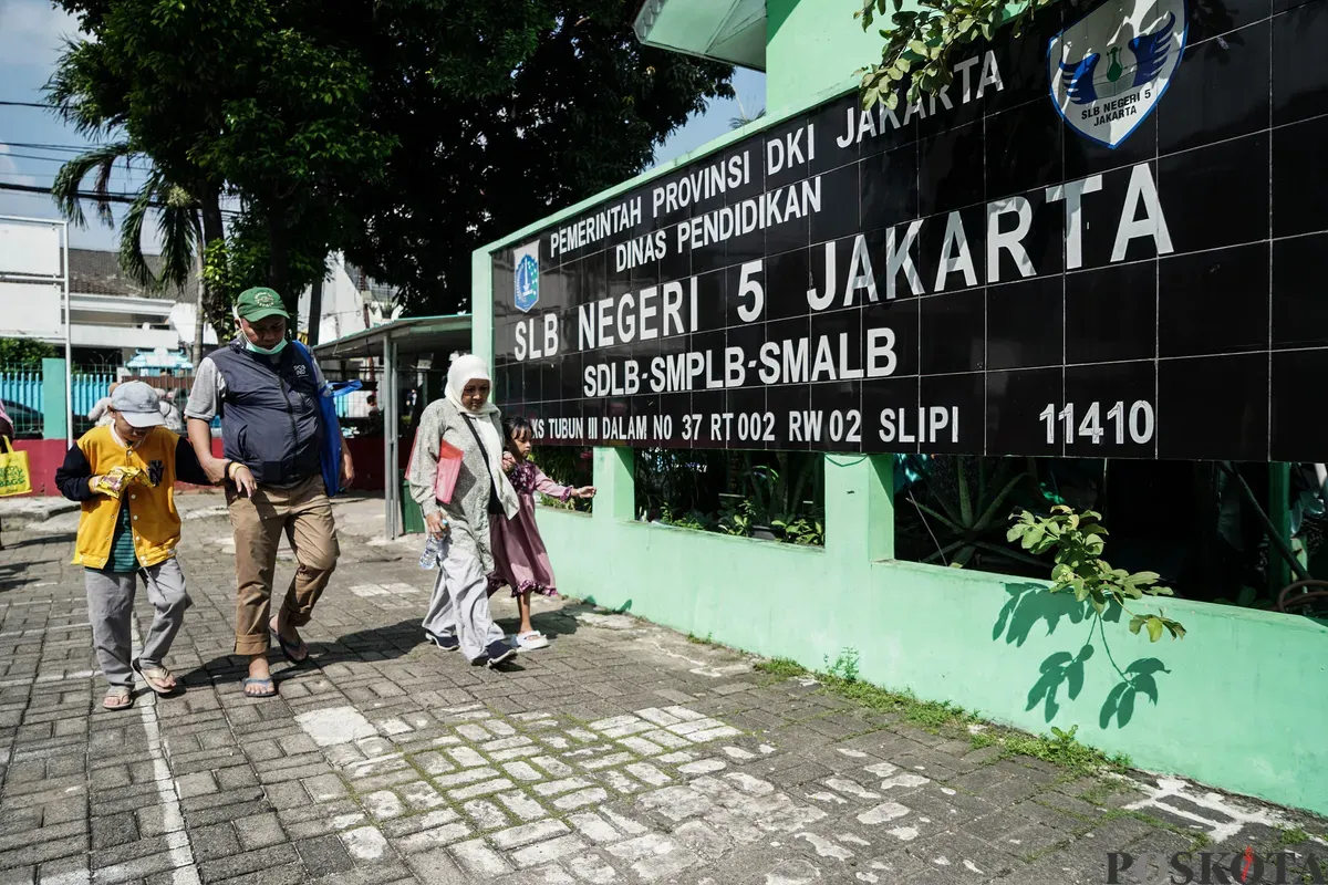 Orang tua dan anak berjalan menuju Posko Sistem Penerimaan Murid Baru (SPMB) SLB Negeri 5 Jakarta, Senin, 16 Juni 2025. (Sumber: Poskota/Bilal Nugraha Ginanjar)