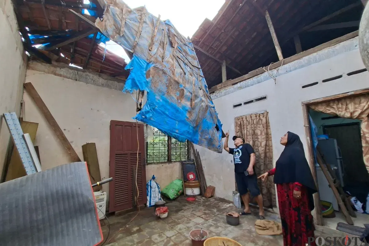 Oma Endah didampingi Ketua RT menujukkan atap yang ambruk tidak tersisa hanya ada sisa terpal untuk menahan air dari banjir di Kota Depok, Jumat, 20 Juni 2025. (Sumber: Poskota/Angga Pahlevi)