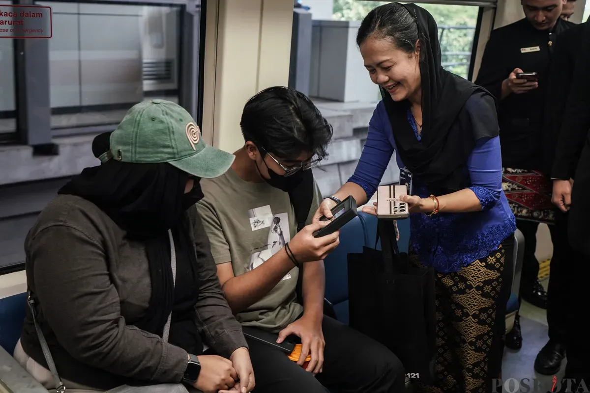 Vice President of Passanger Transport and Information Technology LRT Jabodebek Kristina Oktaviana membagikan KMT LRT Jabodebek edisi khusus Jakarta kepada penumpang di dalam gerbong LRT Jabodebek, Jakarta, Senin, 23 Juni 2025. (Sumber: Poskota/Bilal Nugraha Ginanjar)