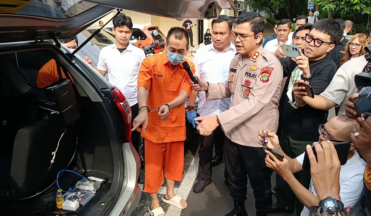 Tersangka kasus illegal access dengan modus SMS palsu menunjukkan alat yang digunakan untuk kejahatan phising di Mapolda Metro Jaya, Selasa, 24 Juni 2025. (Sumber: POSKOTA | Foto: Ali Mansur)