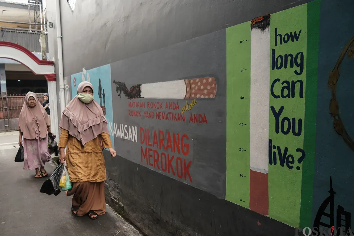 Warga berjalan melewati mural anti rokok di permukiman padat penduduk Matraman, Jakarta, 24 Juni 2025. (Sumber: Poskota/Bilal Nugraha Ginanjar)