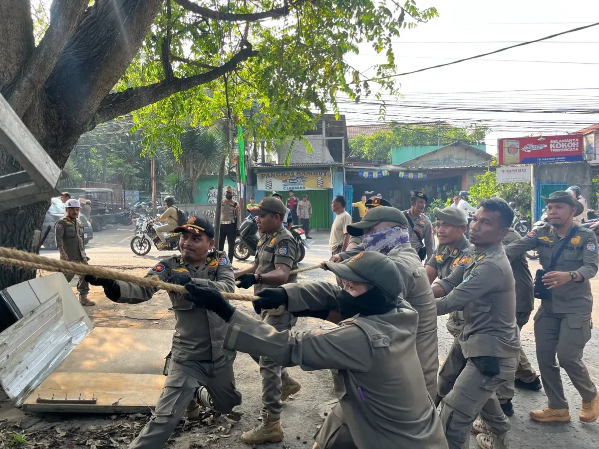Satuan Polisi Pamong Praja (Satpol PP) Kota Depok menertibkan pedagang kaki lima liat mendiringan bangunan permanen atau tidak di sepanjang Jalan Pitara - Cipayung, Kota Depok. (Sumber: Poskota/Angga Pahlevi)