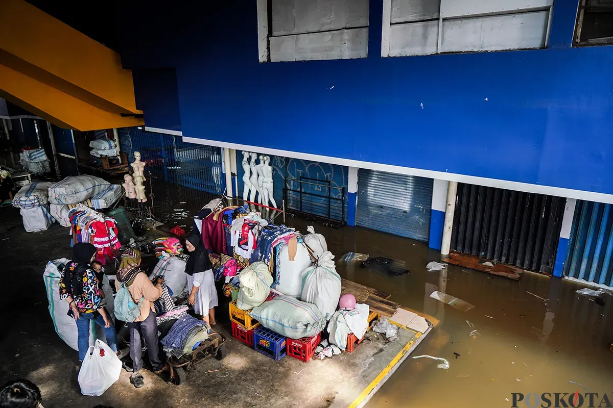 Sejumlah pedagang mengemas dan membawa barang dagangannya menggunakan karung saat bencana banjir melanda di pasar Cipulir, Jakarta Selatan, Selasa, 4 Maret 2025. (Sumber: Poskota/Bilal Nugraha Ginanjar)