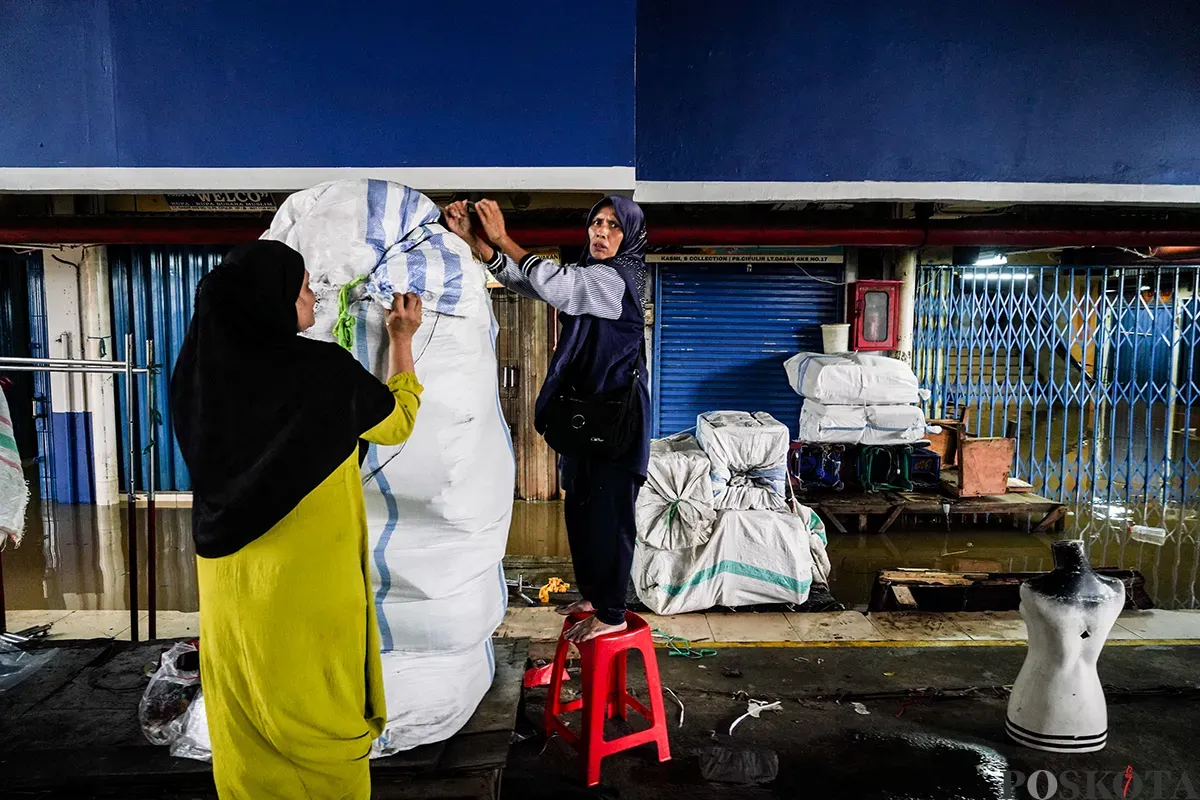 Sejumlah pedagang mengemas dan membawa barang dagangannya menggunakan karung saat bencana banjir melanda di pasar Cipulir, Jakarta Selatan, Selasa, 4 Maret 2025. (Sumber: Poskota/Bilal Nugraha Ginanjar)