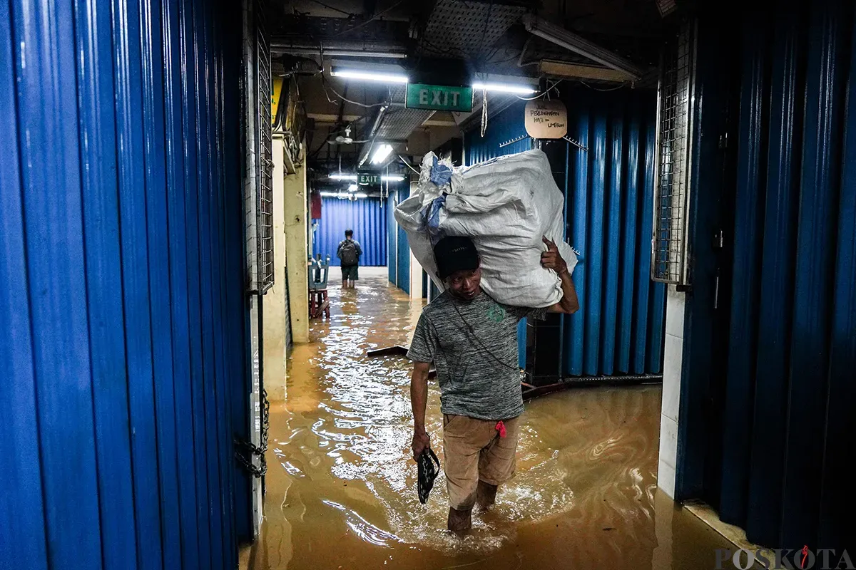 Sejumlah pedagang mengemas dan membawa barang dagangannya menggunakan karung saat bencana banjir melanda di pasar Cipulir, Jakarta Selatan, Selasa, 4 Maret 2025. (Sumber: Poskota/Bilal Nugraha Ginanjar)