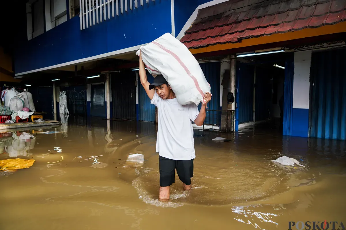 Warga membawa karung berisi dagangan saat banjir di pasar Cipulir, Jakarta Selatan, Selasa, 4 Maret 2025. (Sumber: Poskota/Bilal Nugraha Ginanjar)