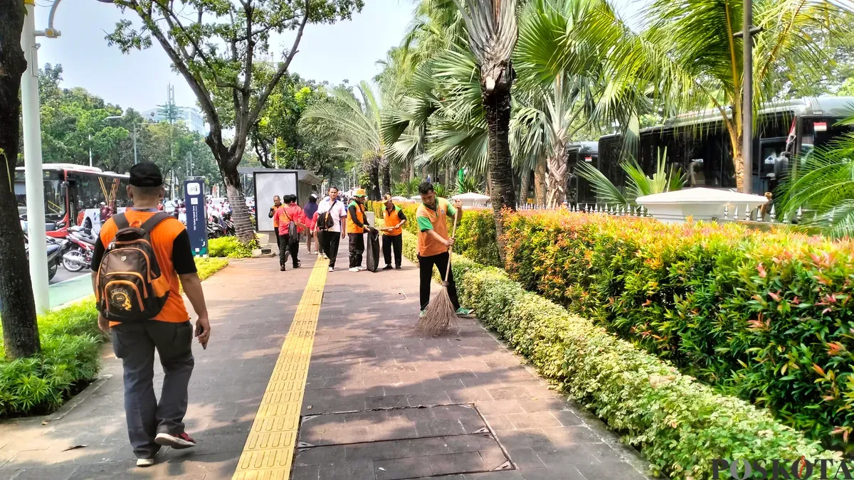 Petugas kebersihan Dinas Lingkungan Hidup (DLH) DKI Jakarta saat membersihkan sampah masa buruh di depan Balai Kota DKI Jakarta. (Sumber: Poskota/M. Tegar Jihad)