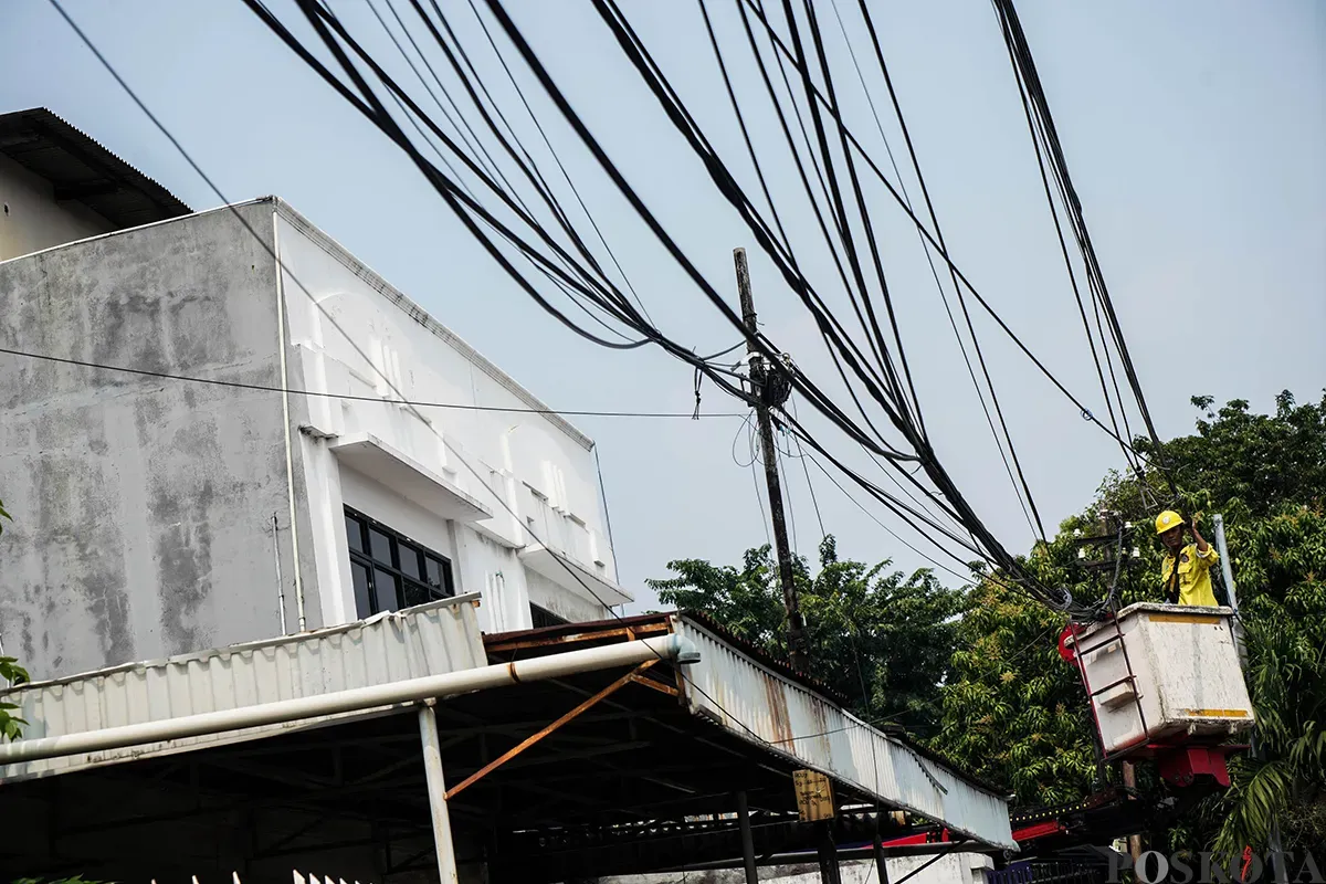 Petugas Dinas Bina Marga memotong kabel utilitas yang dianggap menganggu dan berpotensi membahayakan di kawasan Cideng, Jakarta, Jumat, 1 Mei 2025. (Sumber: Poskota/Bilal Nugraha Ginanjar)