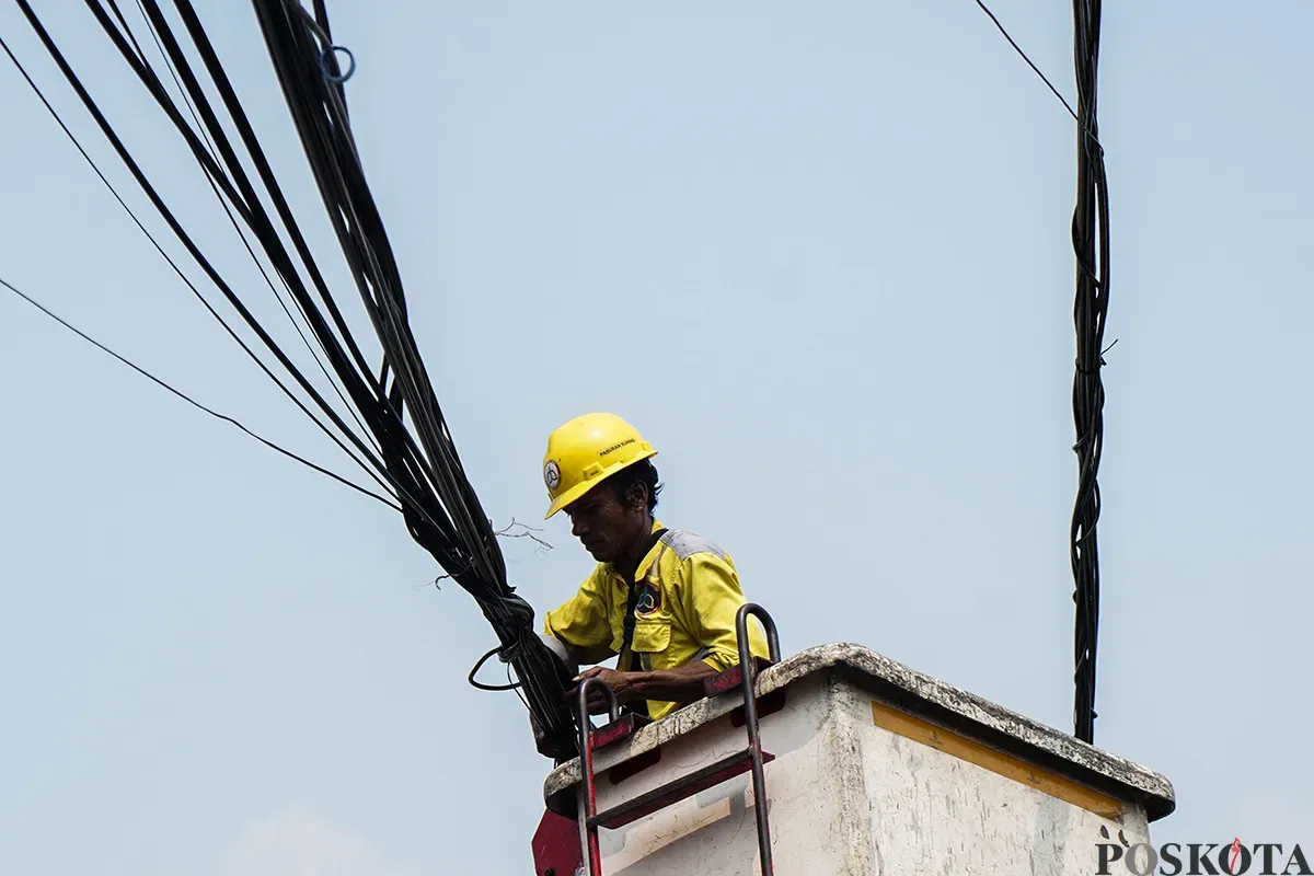 Petugas Dinas Bina Marga memotong kabel utilitas yang dianggap menganggu dan berpotensi membahayakan di kawasan Cideng, Jakarta, Jumat, 1 Mei 2025. (Sumber: Poskota/Bilal Nugraha Ginanjar)